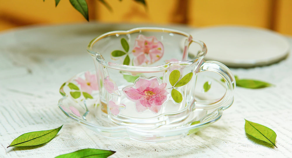 Handcrafted pressed flower relief glass coffee cup and saucer on cream marble.