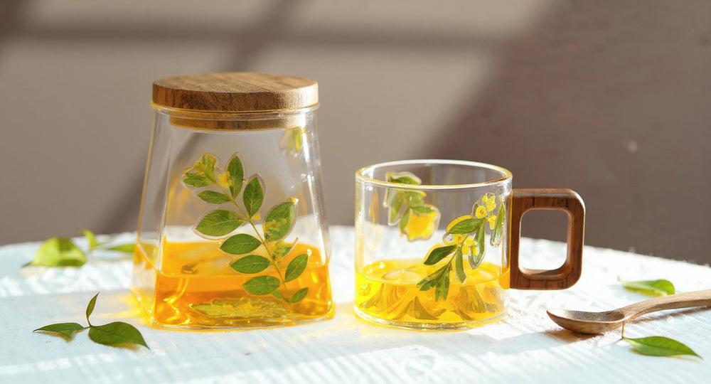 Handmade Pressed Flower Glass Mug with Walnut Handle on wooden tray beside eucalyptus.