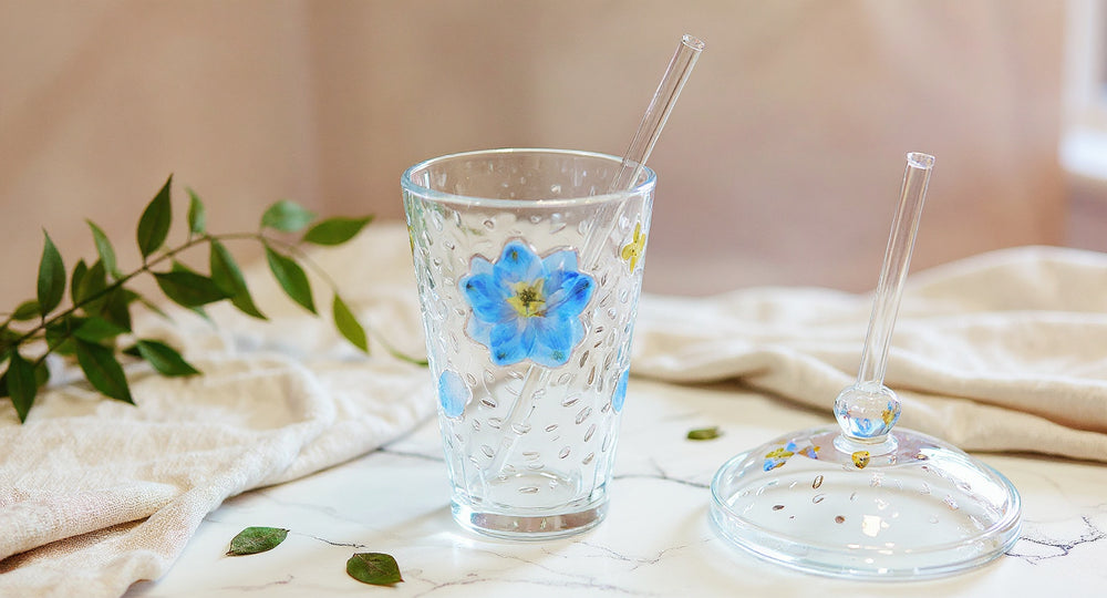 Handmade Floral Glass Cup with real pressed flowers, saucer, lid, and straw on white marble.