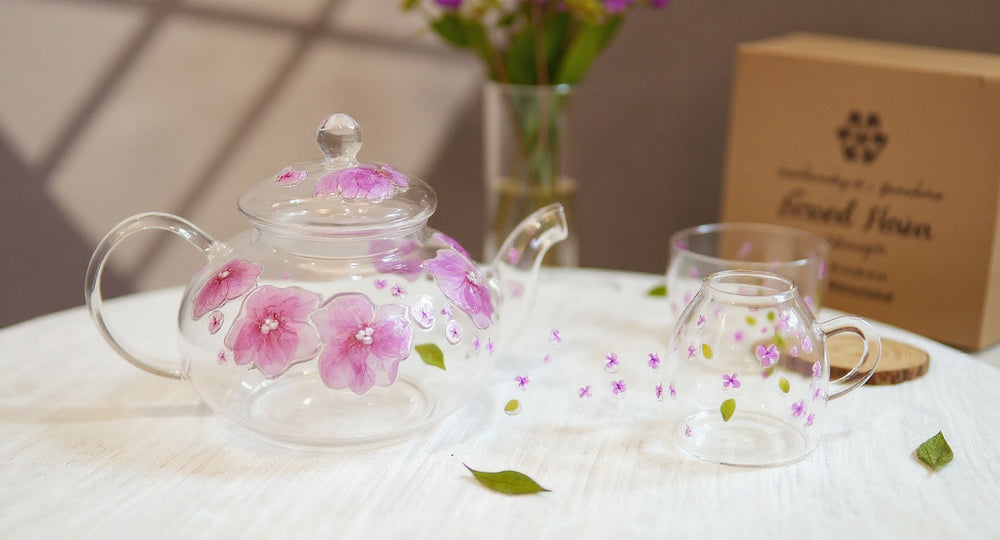 Handmade Pressed Flower Glass Teapot & Cup Set with botanical sprigs on linen.
