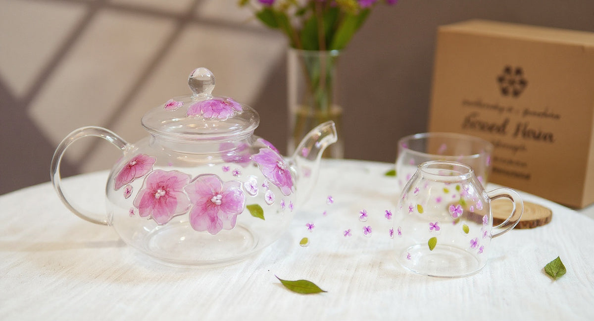 Handmade Pressed Flower Glass Teapot & Cup Set with botanical sprigs on linen.