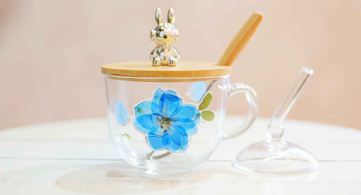 Handcrafted Floral Glass Cup with Real Preserved Flowers and glass lid on white marble.