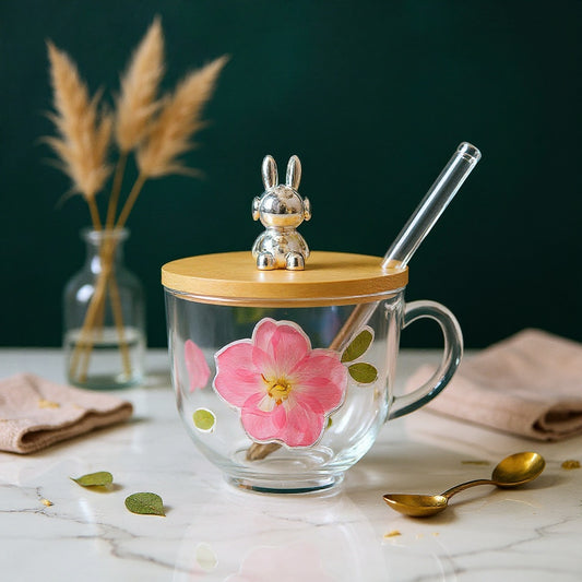 A handcrafted glass cup with real preserved flowers on a marble surface with natural lighting and a bold sage background.