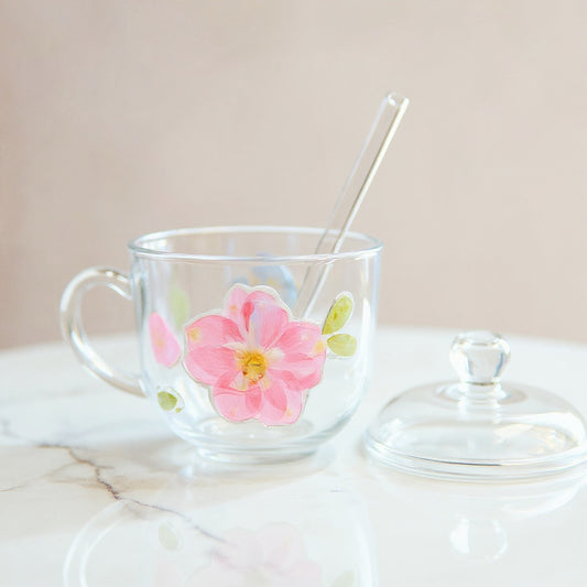 Clear glass cup with 3D floral relief, lid, and straw on white marble, soft lighting, minimalist scene.