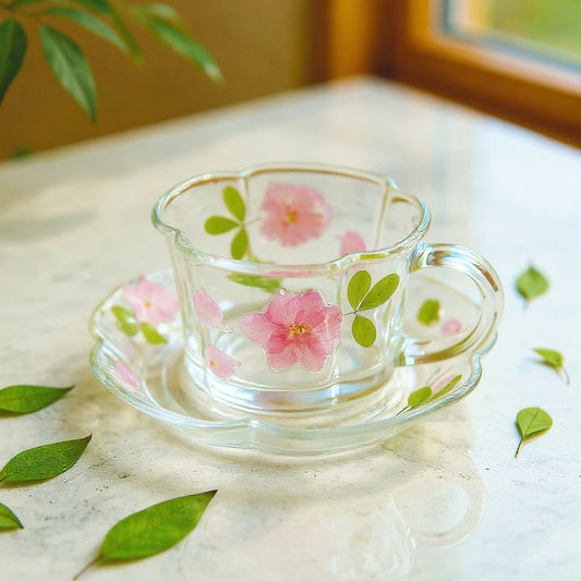 Luxury floral glass teacup and saucer with embedded real botanicals on a marble surface, soft natural light, editorial still life.