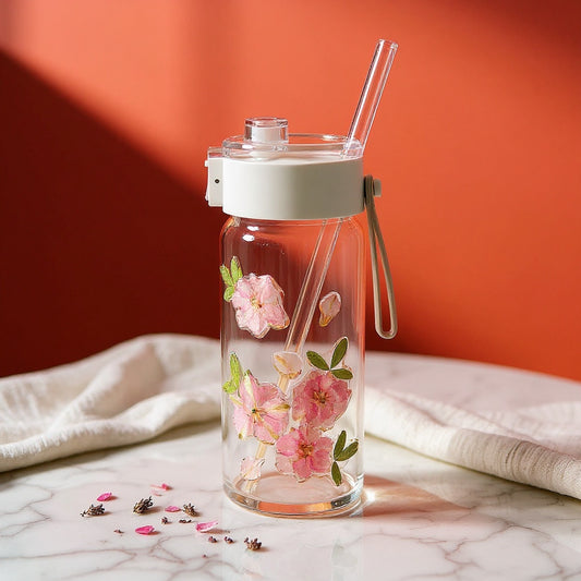 Clear glass tumbler with pressed flowers on marble, lavender petals, against amber gradient