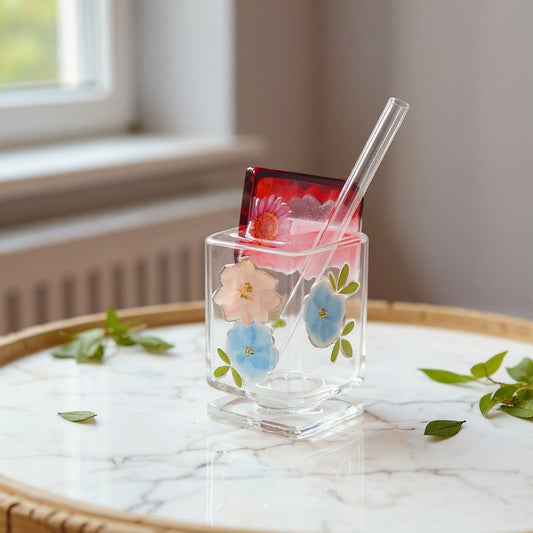 Artisan glass cup with botanical design on marble surface in soft natural light