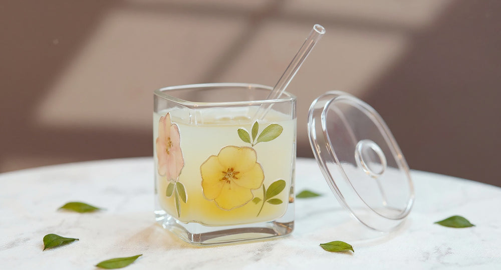 Handcrafted whiskey glass with real preserved flowers on marble table