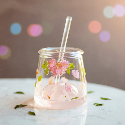 Floral tea glass cup aesthetic with raised flowers on marble surface, soft bokeh background, wide editorial composition.