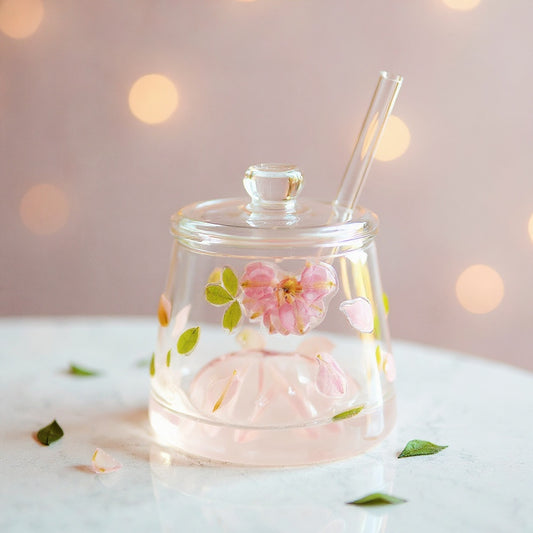 Clear glass tumbler with raised floral design, lid, and straw on marble surface.