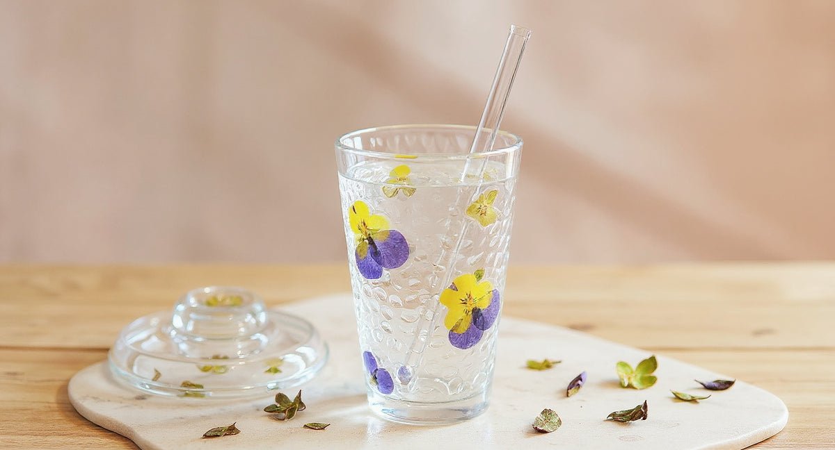 Handmade Real Flower Glass Cup with lid and straw on oak table with dried petals