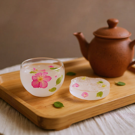 Handcrafted floating flower tea cup with cherry blossom petals on a wooden tea tray, soft natural lighting and clay teapot.