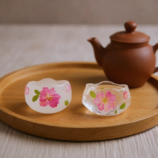 Preserved cherry blossom petal tea cup on a wooden tea tray with a clay teapot, soft natural light, editorial style.