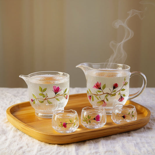 Complete glass tea set with gaiwan, pitcher and four cups on a wooden tray, showcasing ice-ripple hammered glass with pink rose petal and green leaf 3D texture, soft natural light and steam.