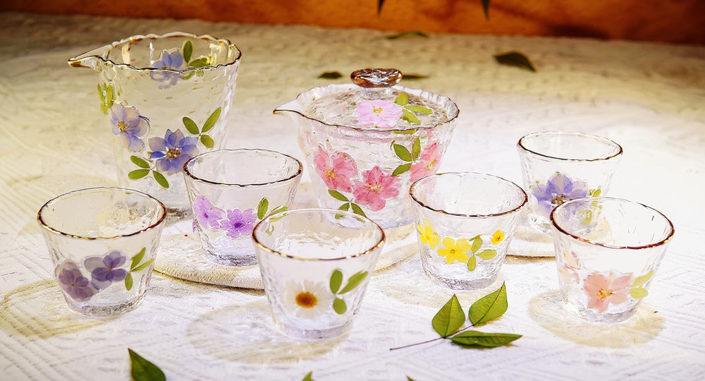 Handmade hammered glass gaiwan tea set with real pressed flowers and gold rim on wood tray.