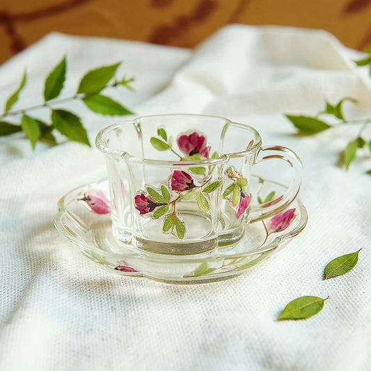 Delicate clear glass teacup with 3D botanical relief on a linen tablecloth with fresh botanicals.
