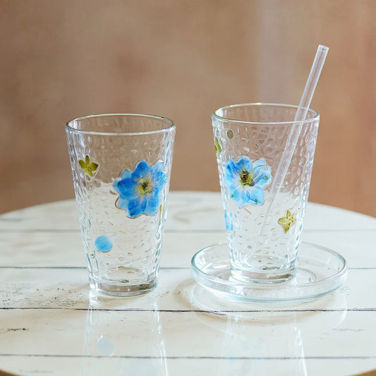 Clear glass cup with preserved floral relief on marble surface