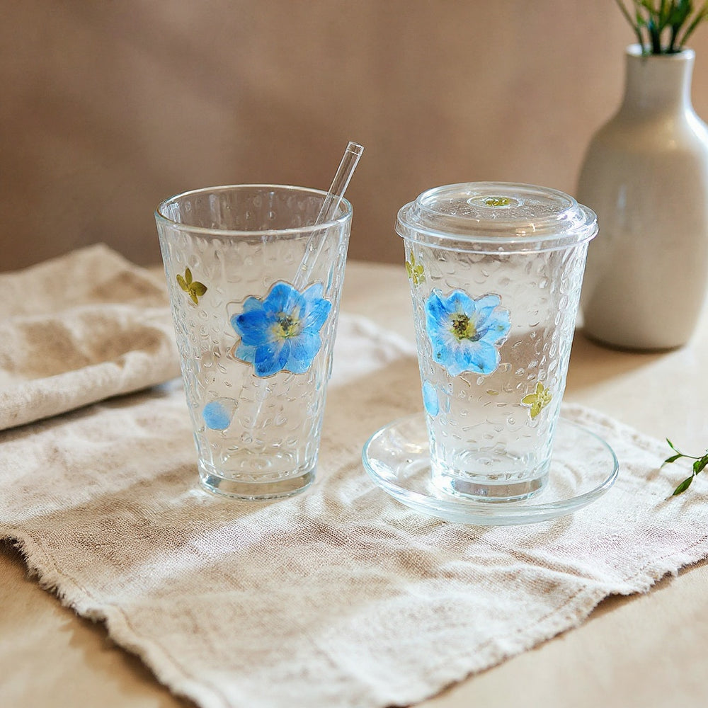 Real pressed flower glass cup set on a linen surface in soft natural light.