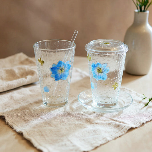 Real pressed flower glass cup set on a linen surface in soft natural light.