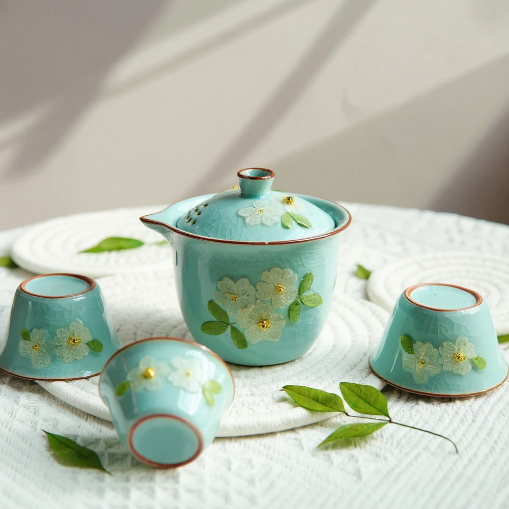Artisan celadon tea ceremony set with embedded botanicals on linen, bathed in soft natural light.