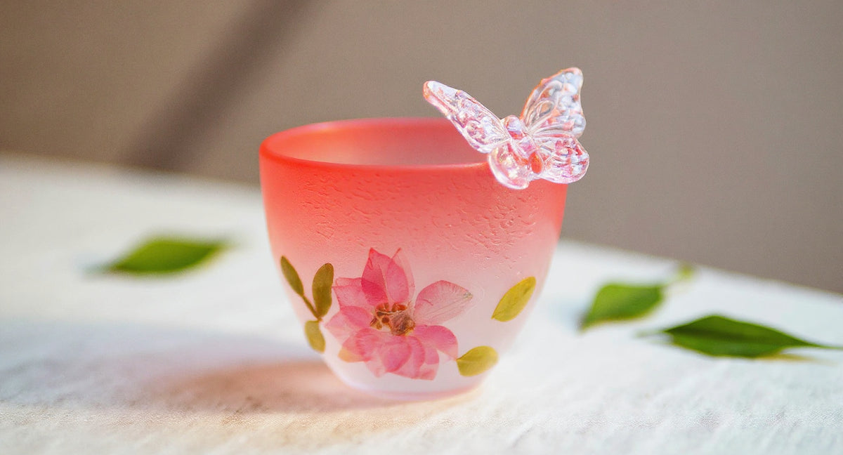 Handmade gradient pink butterfly glass cup with preserved flowers on linen