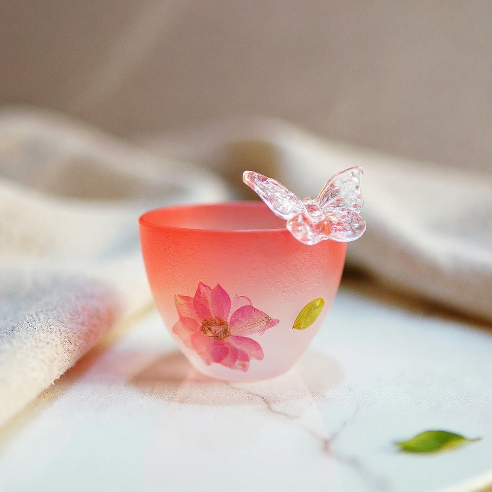 Handcrafted botanical glass cup with dried flowers and butterfly resin motif on natural stone surface