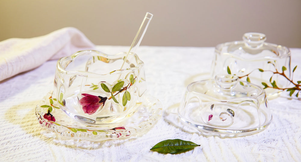 Handcrafted glass teacup saucer set with preserved pink and red roses on marble